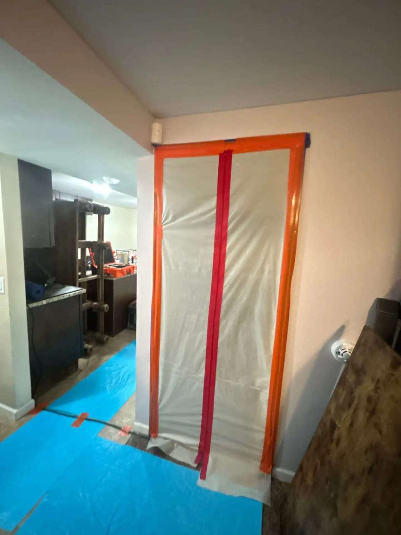Taped containment doorway in a home with a protective runner on the floor