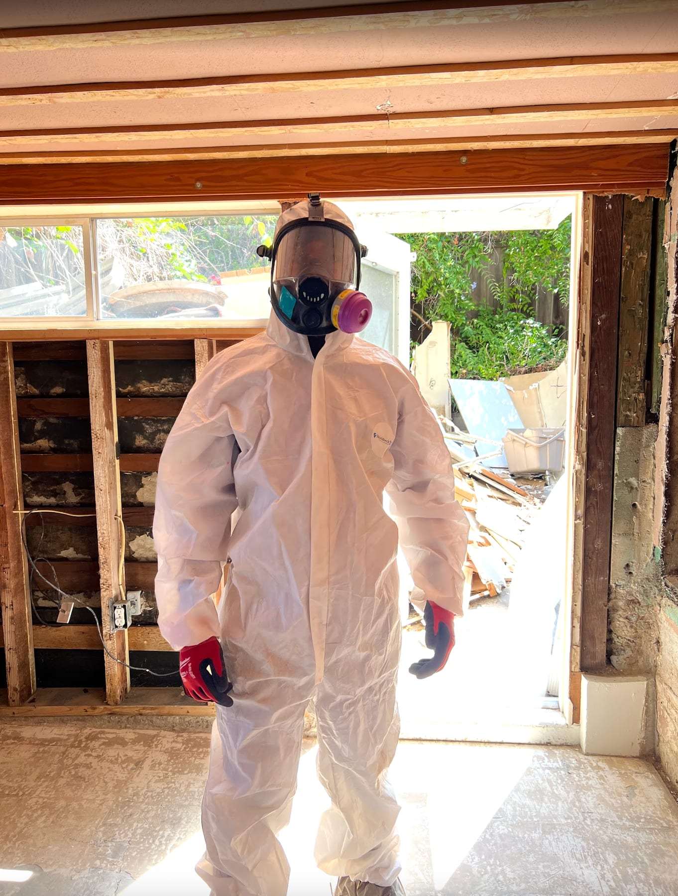Worker in a protective suit and respirator in a gutted room